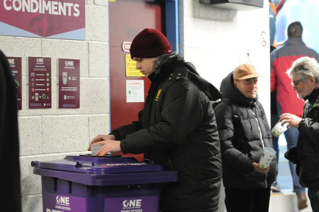 fan putting their reusable cup into a reusable cup bin at a football stadium